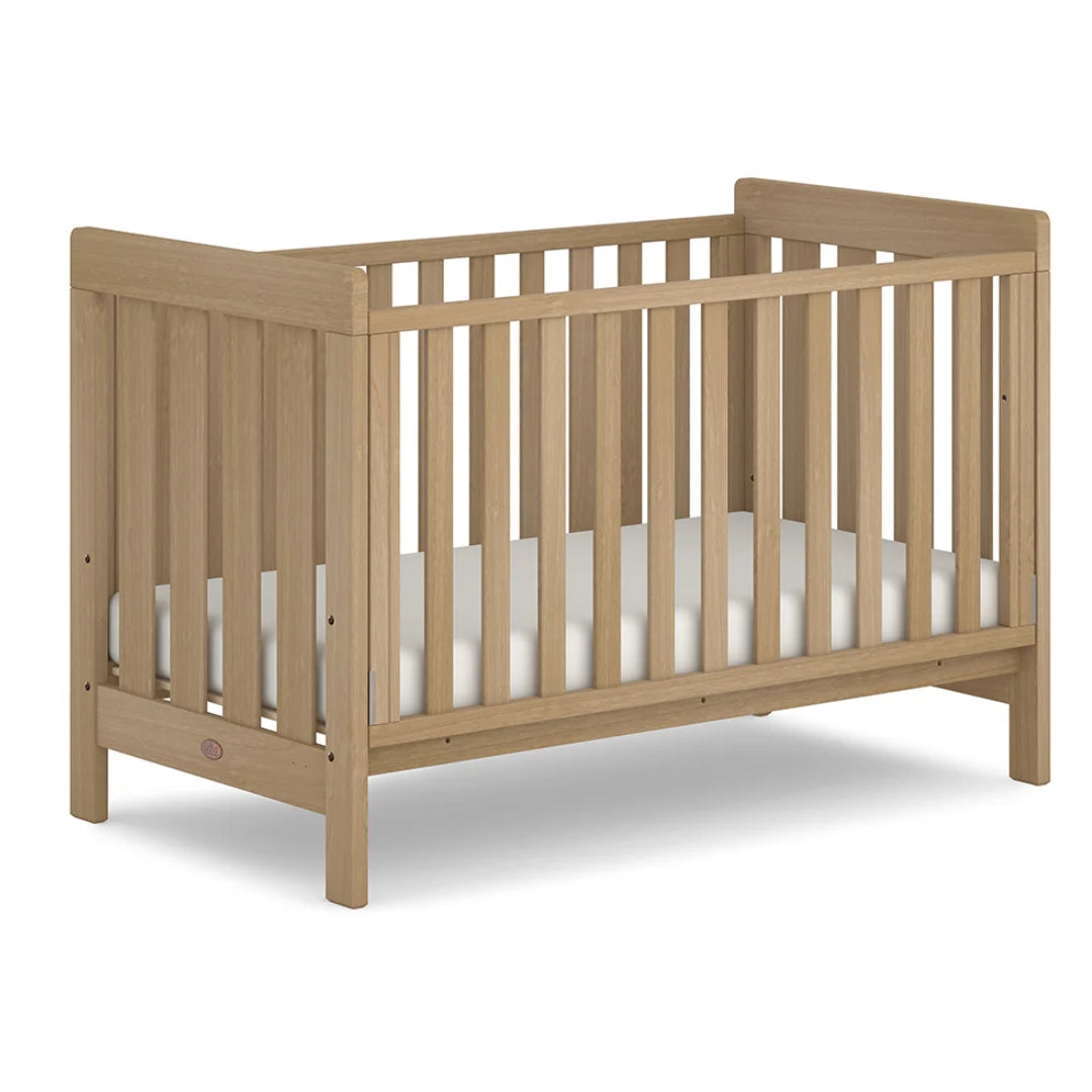Wooden crib with white mattress on a white background